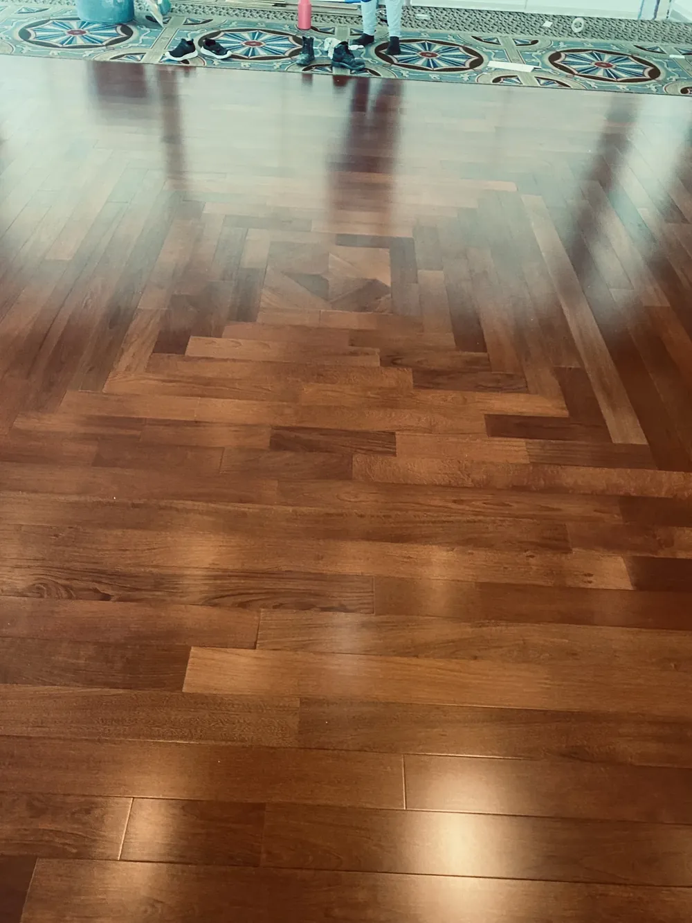 Solid wood flooring with a custom geometric medallion inlay, bordering a decorative inset pattern